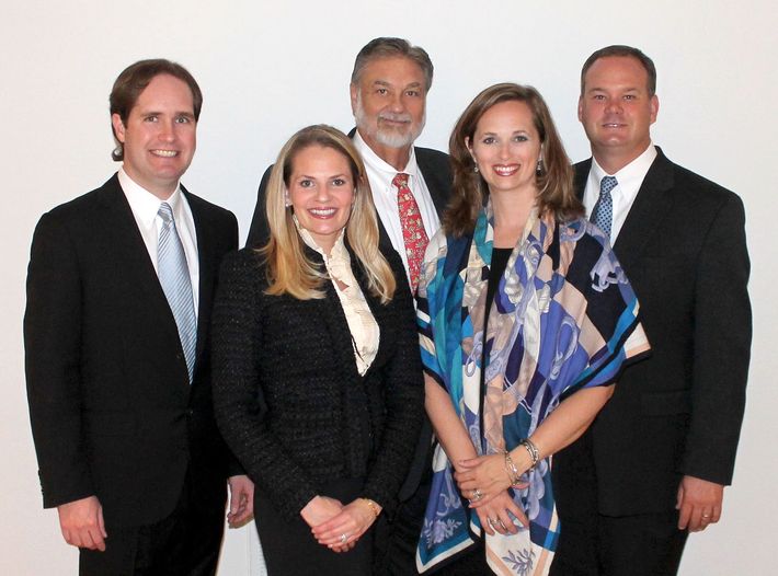 A woman is sitting at a table writing in a notebook next to a laptop.