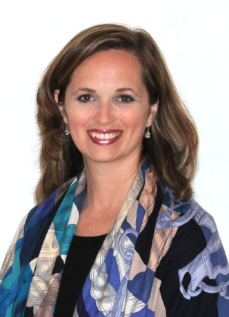 A man in a grey shirt is smiling for the camera