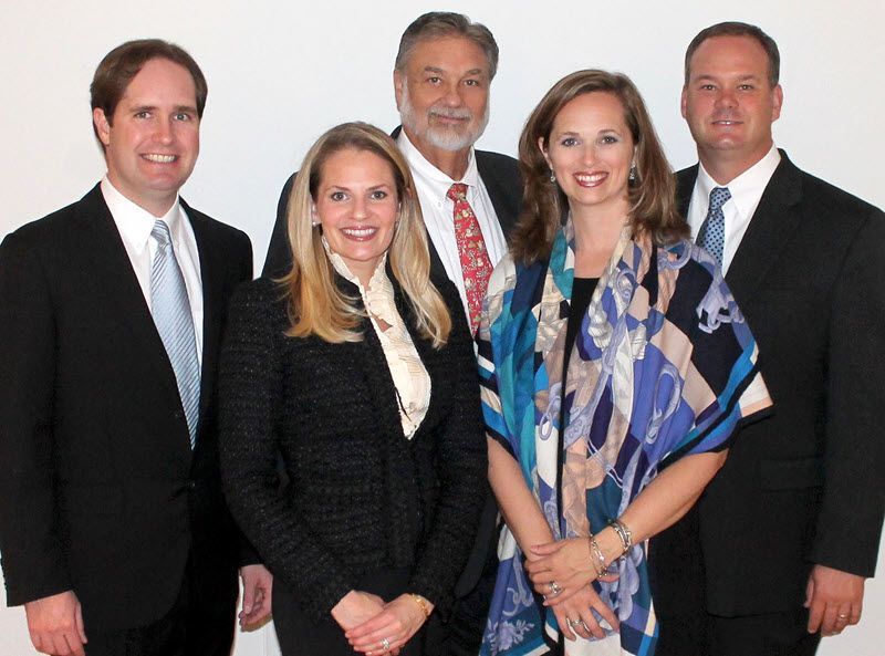 A woman is sitting at a table writing in a notebook next to a laptop.