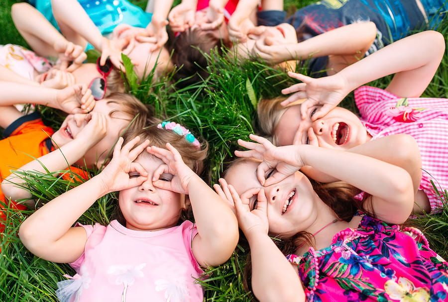 A Group of Children Are Laying in the Grass Making Funny Faces — Mt Ousley Pre School in Fairy Meadow, NSW