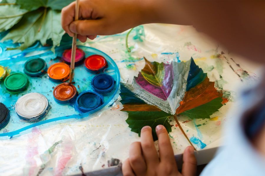 A Child is Painting a Leaf With Watercolors — Mt Ousley Pre School in Fairy Meadow, NSW
