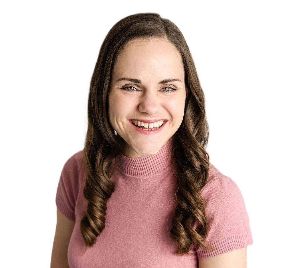 Nadia Liebenberg Smiling in a pink top with arms crossed against a white background