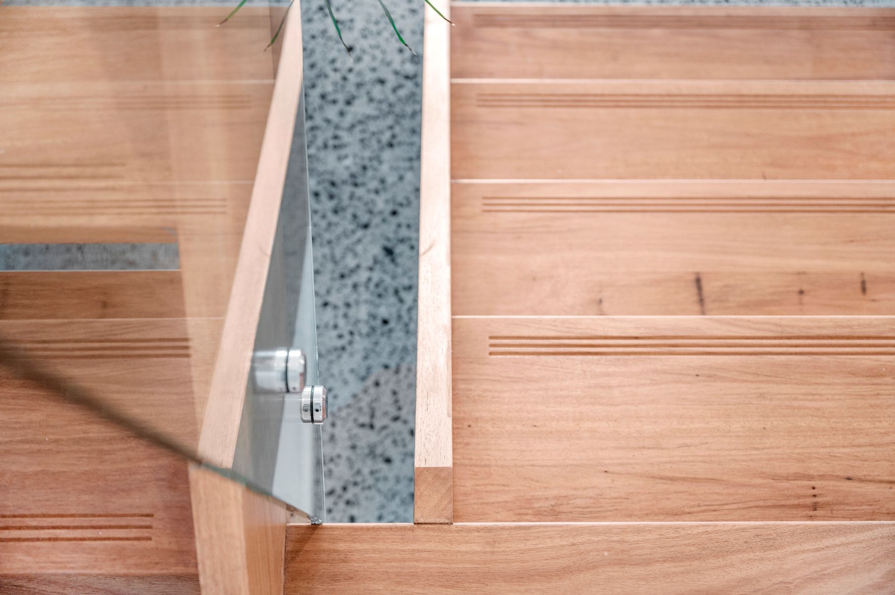 A Close Up of a Wooden Staircase With a Glass Railing — Plumbe Joinery in Coffs Harbour, NSW
