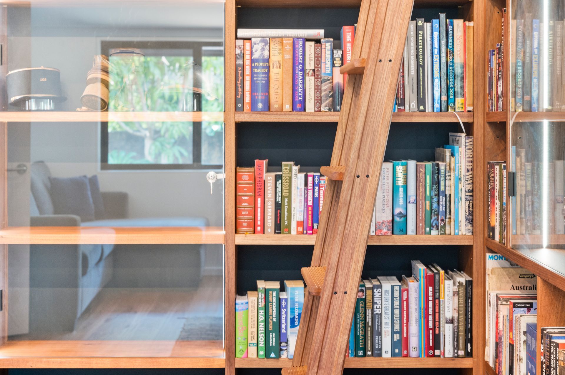 A Bookshelf With a Ladder Leading Up to It Filled With Books — Plumbe Joinery in Coffs Harbour, NSW
