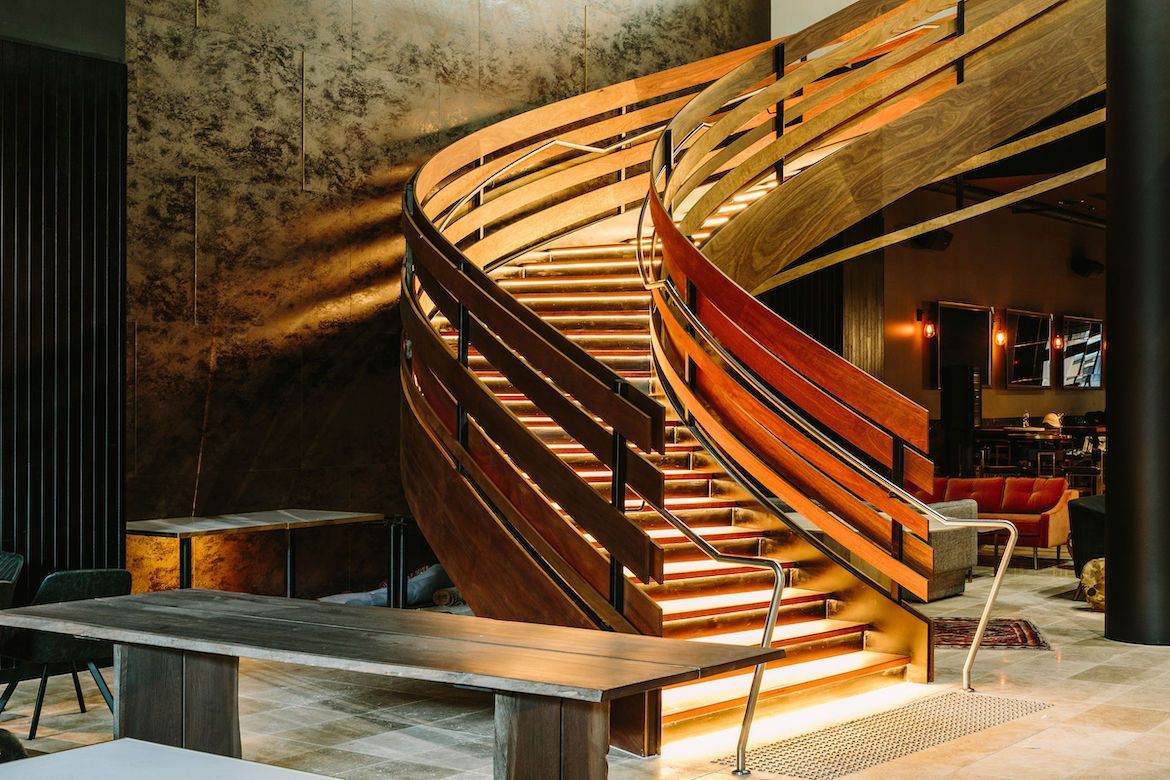 A Wooden Spiral Staircase in a Room With Tables and Chairs — Plumbe Joinery in Coffs Harbour, NSW