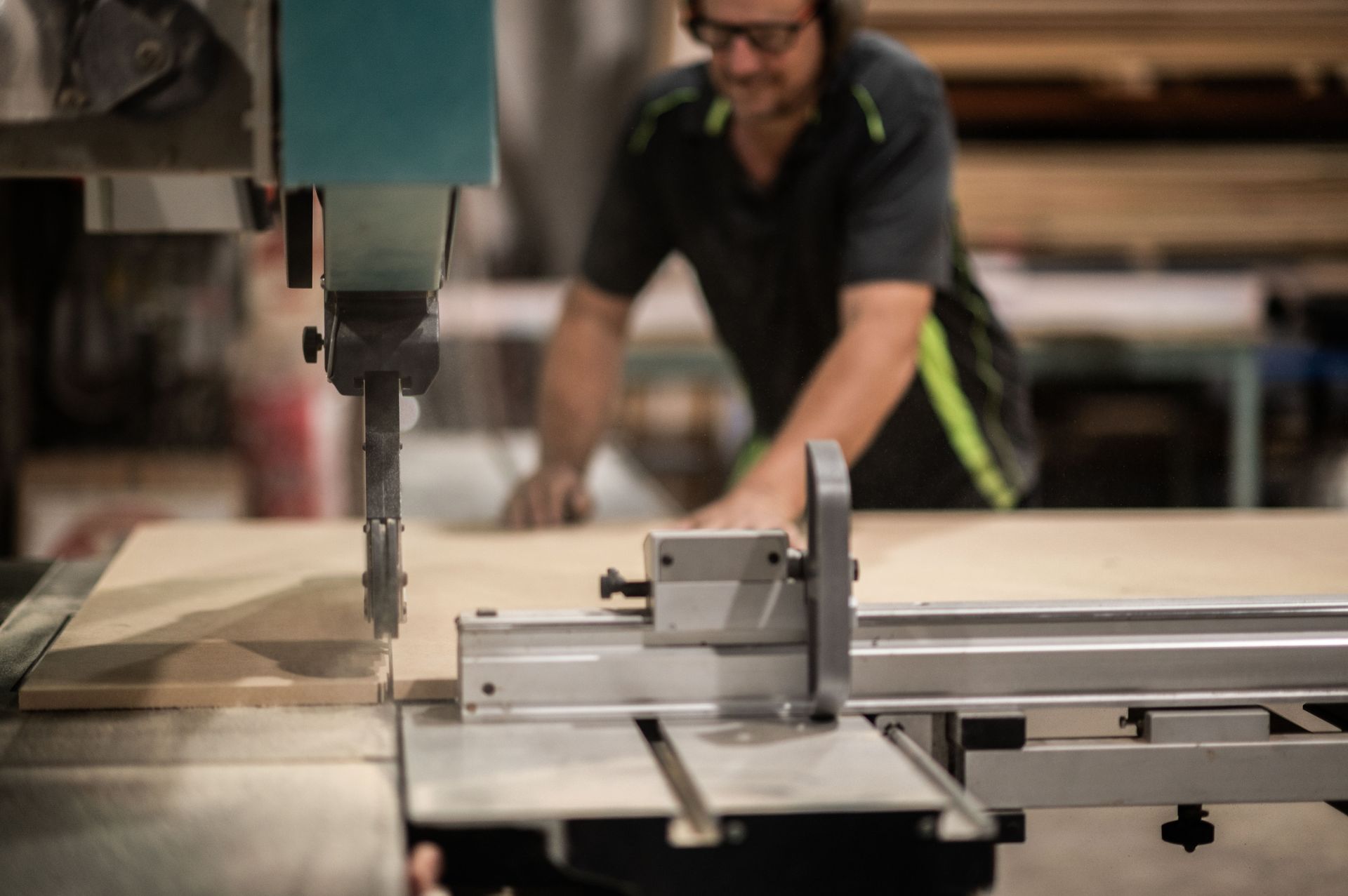 A Man is Using a Band Saw to Cut a Piece of Wood — Plumbe Joinery in Coffs Harbour, NSW