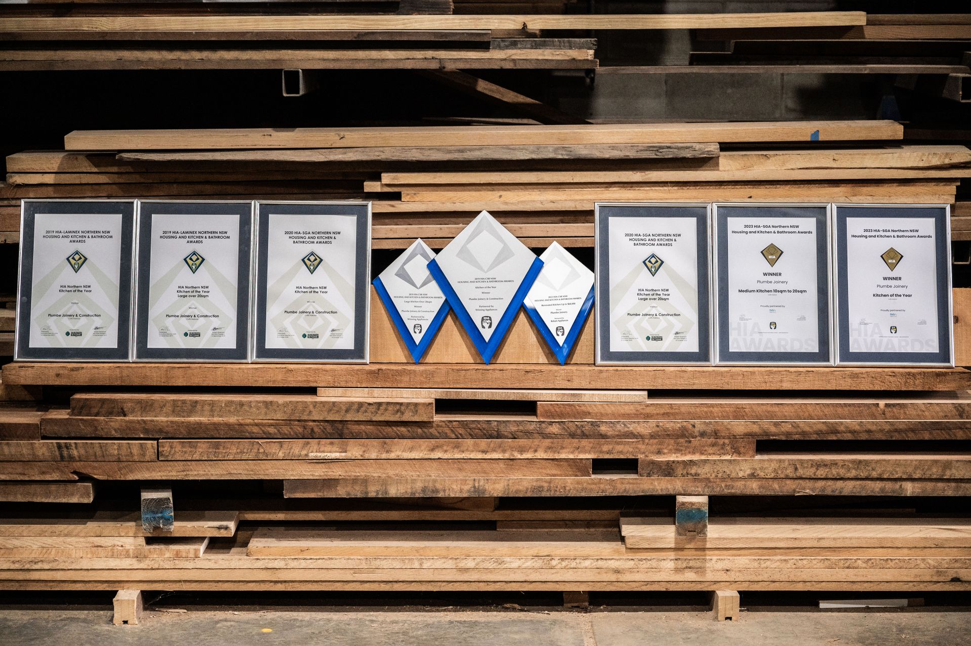 A Stack of Wooden Boards With Certificates on Them — Plumbe Joinery in Coffs Harbour, NSW