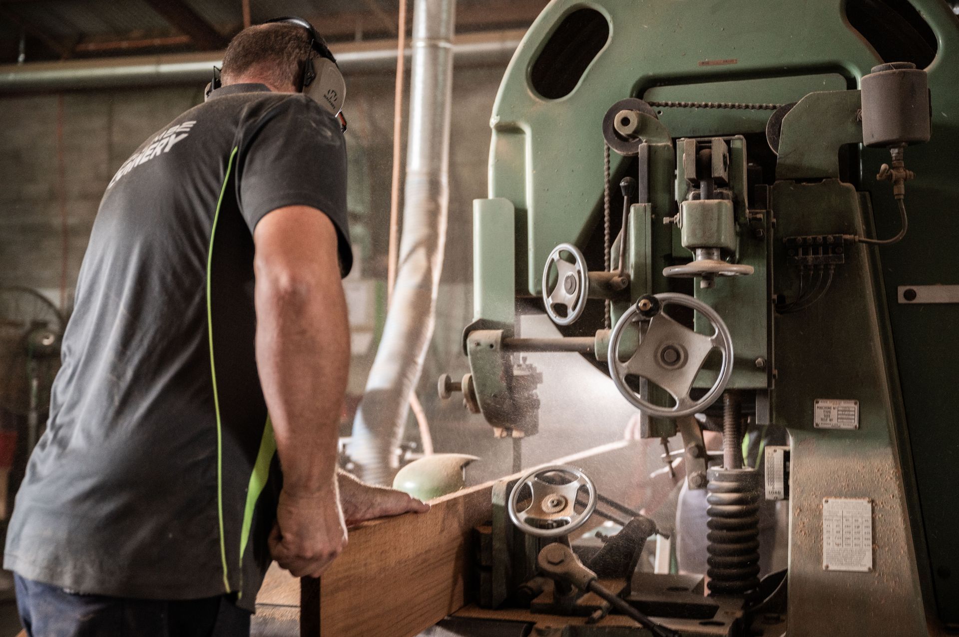 A Man is Using a Machine to Cut a Piece of Wood — Plumbe Joinery in Coffs Harbour, NSW