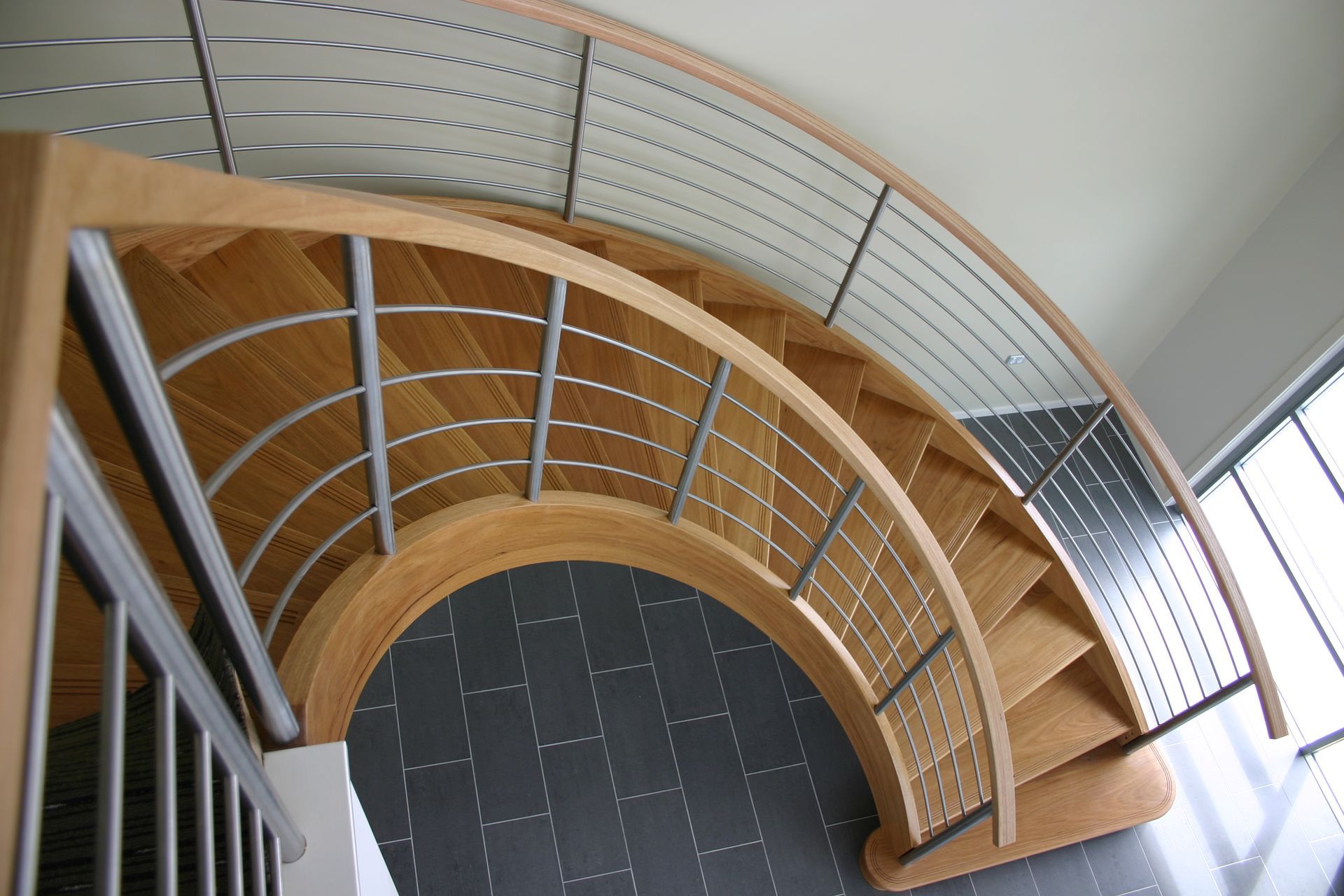 A Wooden Spiral Staircase With a Metal Railing — Plumbe Joinery in Coffs Harbour, NSW