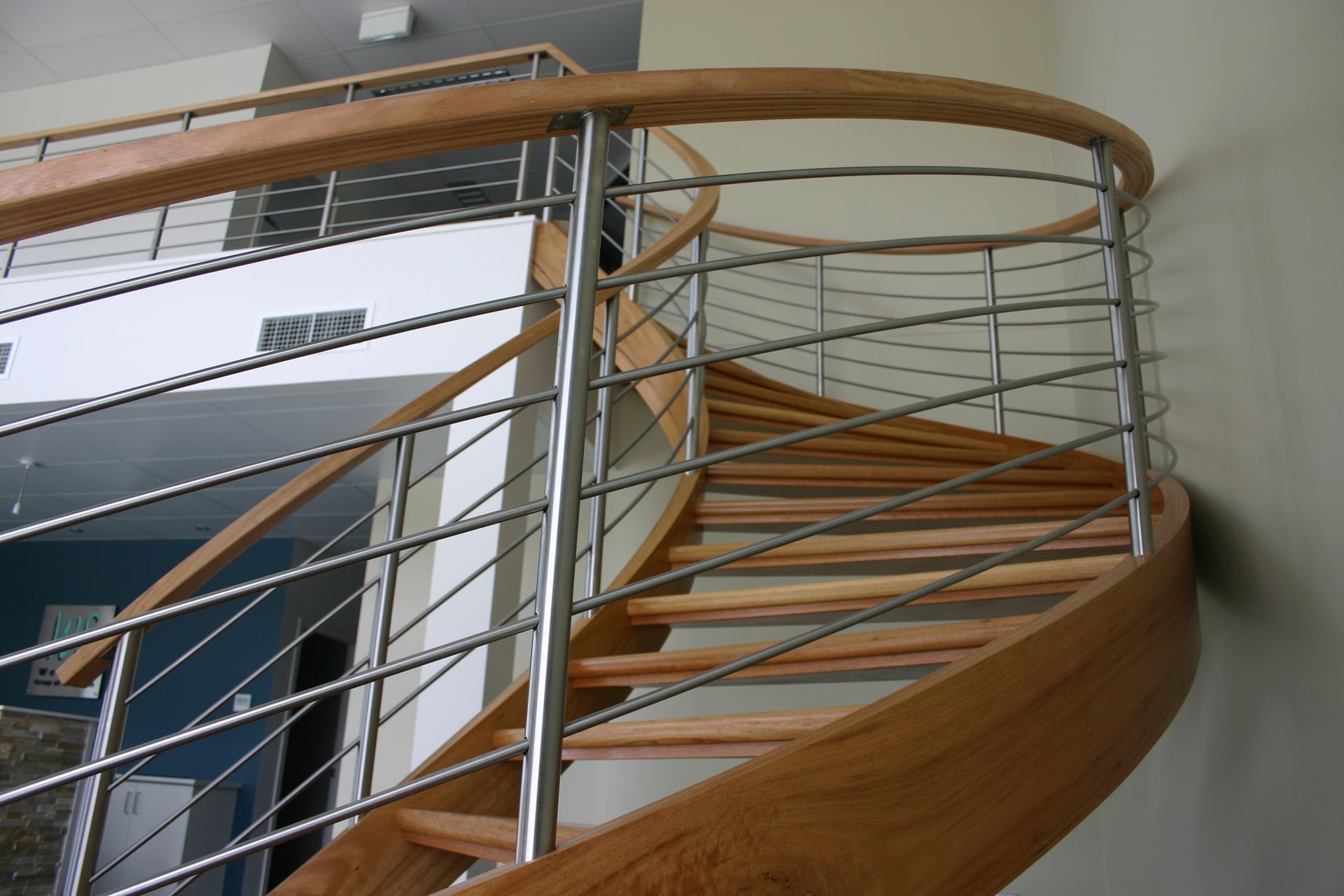 A Wooden Spiral Staircase With a Metal Railing — Plumbe Joinery in Coffs Harbour, NSW