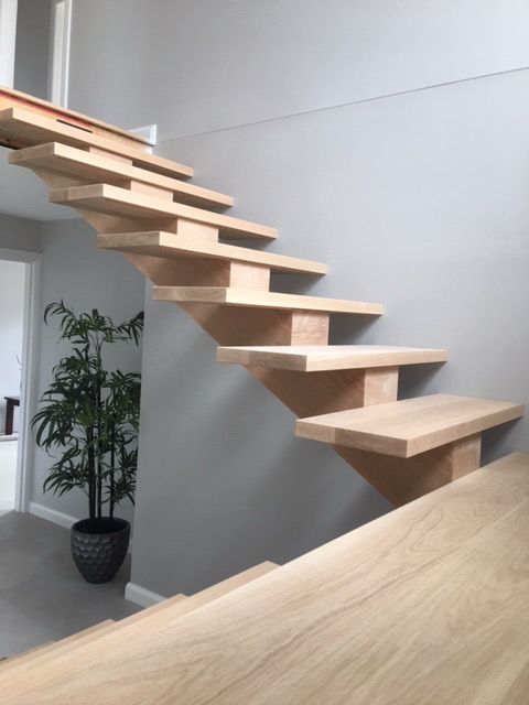 A Wooden Staircase With a Plant in the Background — Plumbe Joinery in Coffs Harbour, NSW