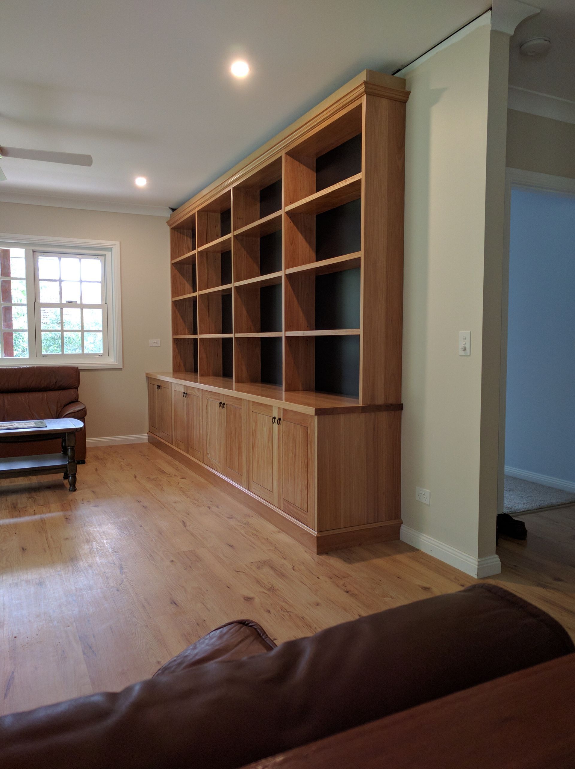 A Living Room With Wooden Shelves and a Couch — Plumbe Joinery in Coffs Harbour, NSW