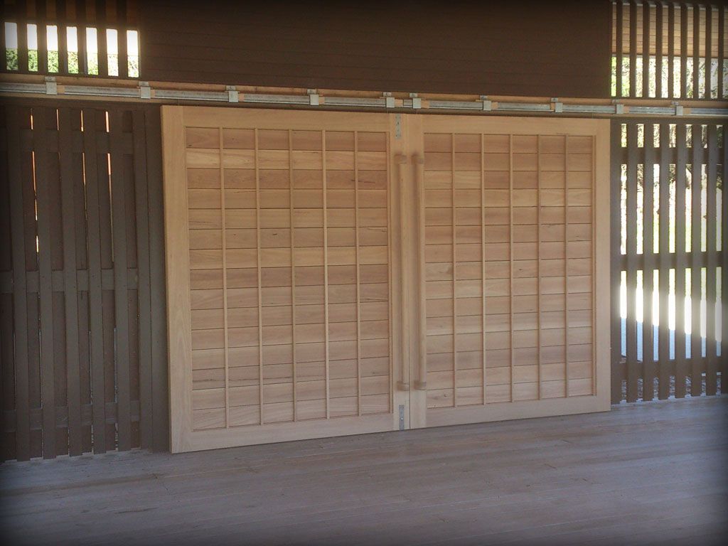 A Wooden Wall With a Fence Behind It — Plumbe Joinery in Coffs Harbour, NSW