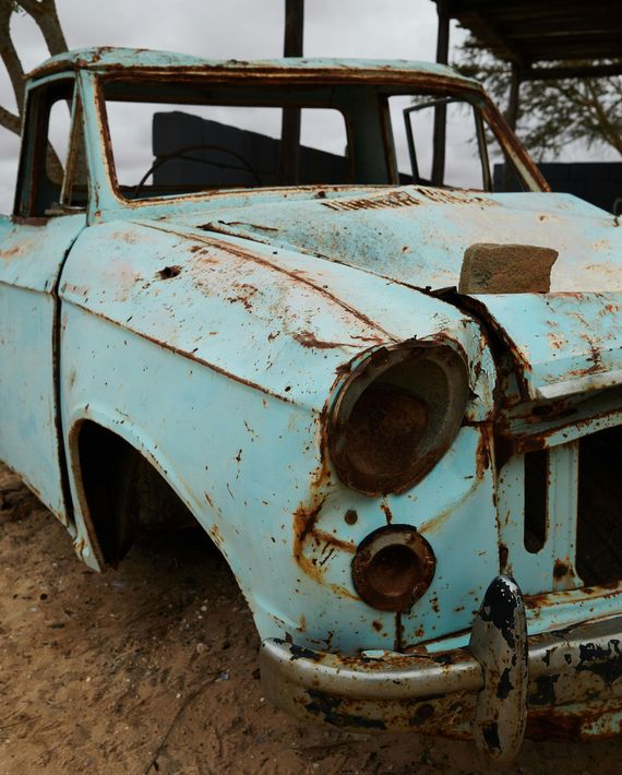 Rusty, light blue vintage pickup truck abandoned outdoors.