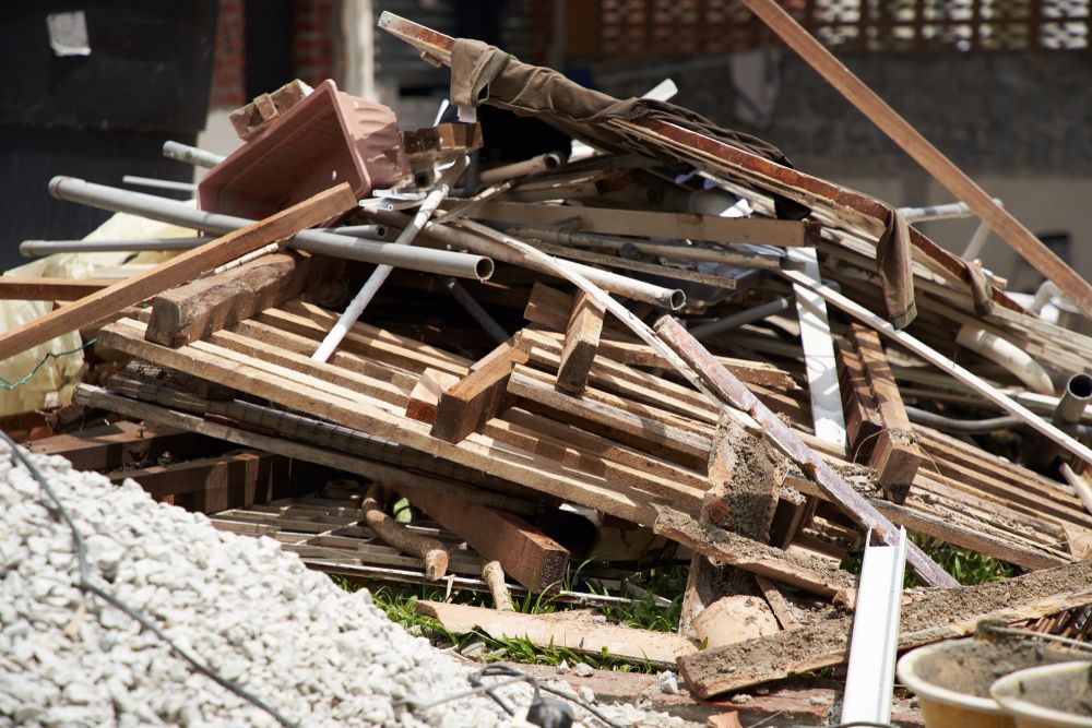Pile of construction debris including wood, metal pipes, and rubble in an outdoor setting.
