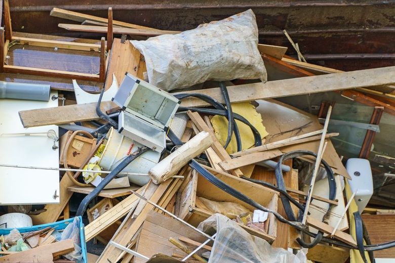 Pile of construction debris: wood scraps, wires, electrical components, and a bag of sawdust.