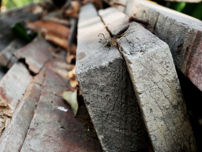 Pile of weathered gray and brown wooden planks, close-up view.