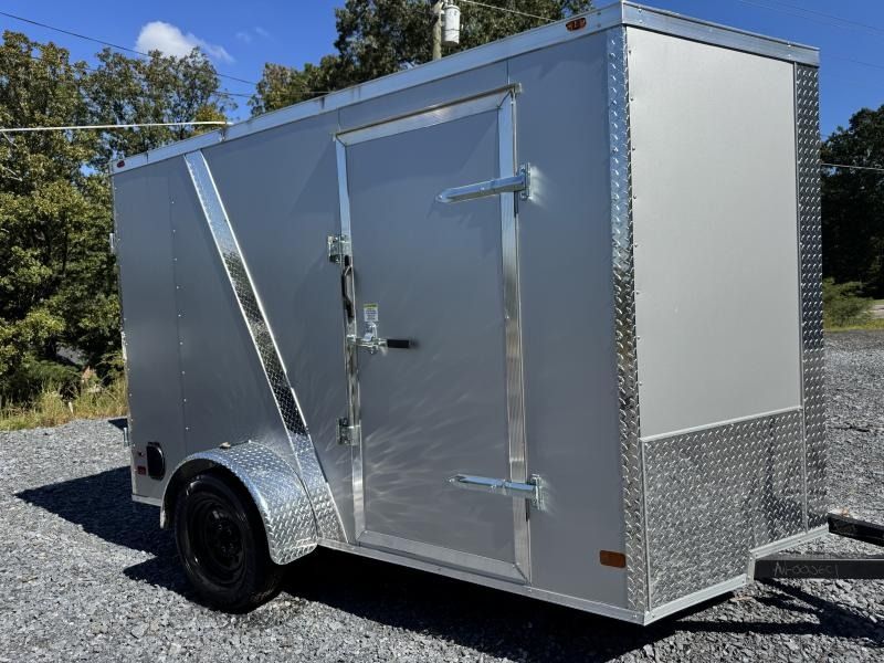 Silver enclosed cargo trailer with a door and black wheel parked outdoors.