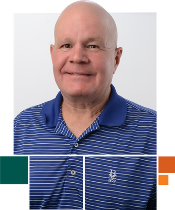 A bald man wearing a blue polo shirt is smiling for the camera.