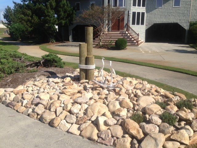 Cobblestone river rock surrounding a nautical post with lawn decor of sea birds.