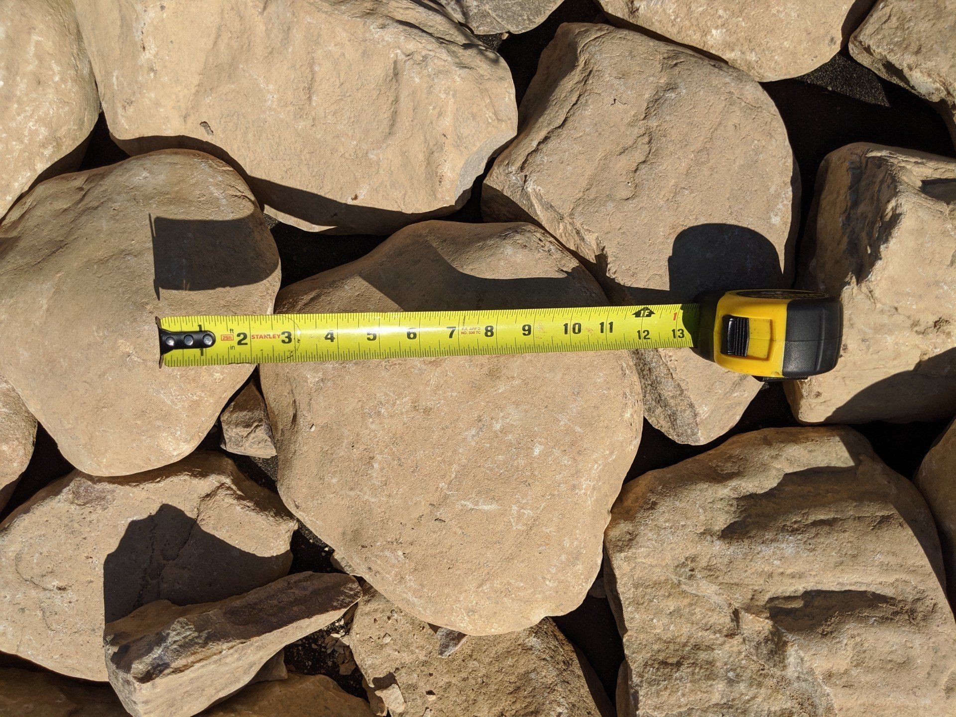 Large river rock with a tape measure showing they are at least  9 inches wide.