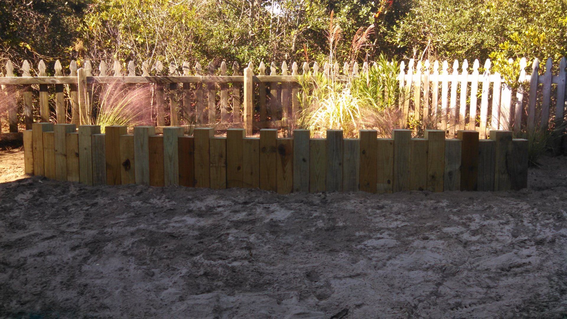 6 x 6 Square Posts borders a garden bed of mulch and trees.