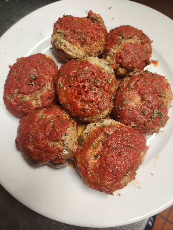 Breadsticks in a basket with a red and white checkered liner on a wooden table.