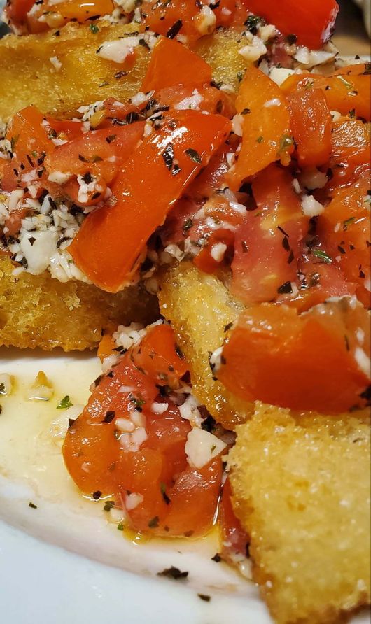 Sandwich with white cheese, greens, and paper wrapping, on a plate outdoors.
