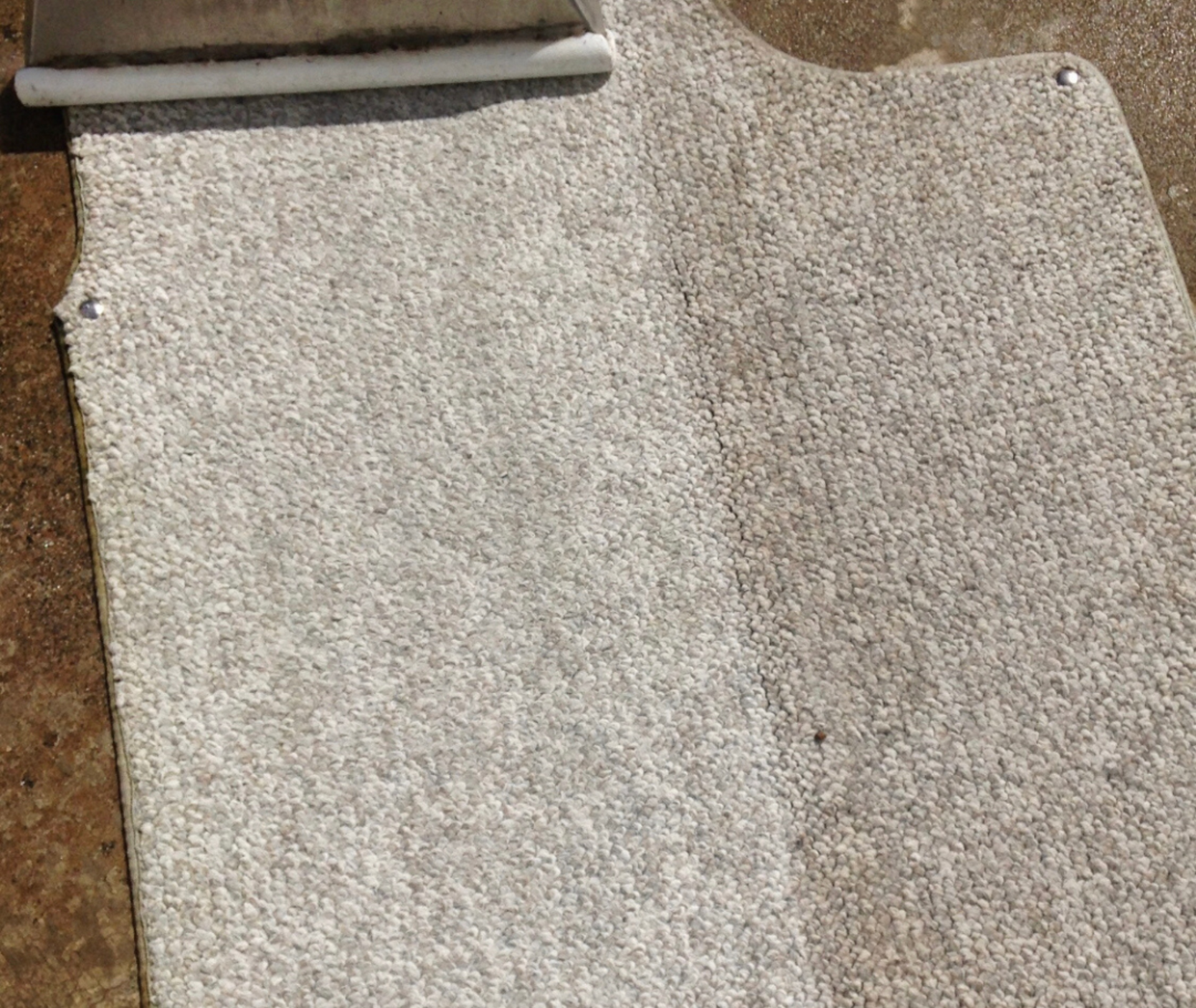 A piece of carpet is being cleaned with a vacuum cleaner.