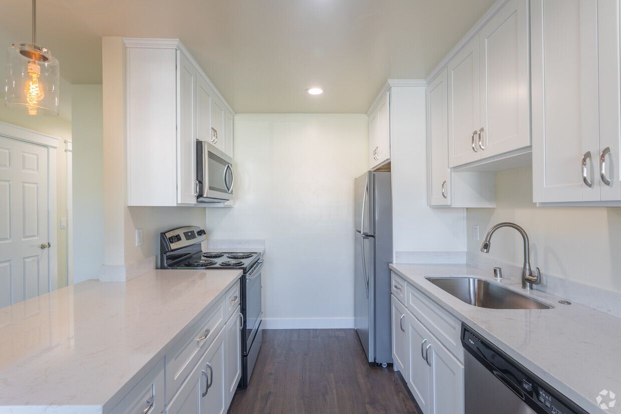 A kitchen with white cabinets , stainless steel appliances , a sink , and a refrigerator.