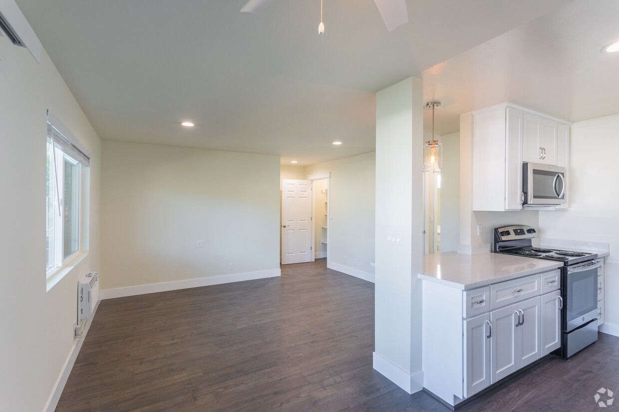 An empty apartment with a kitchen and a living room.
