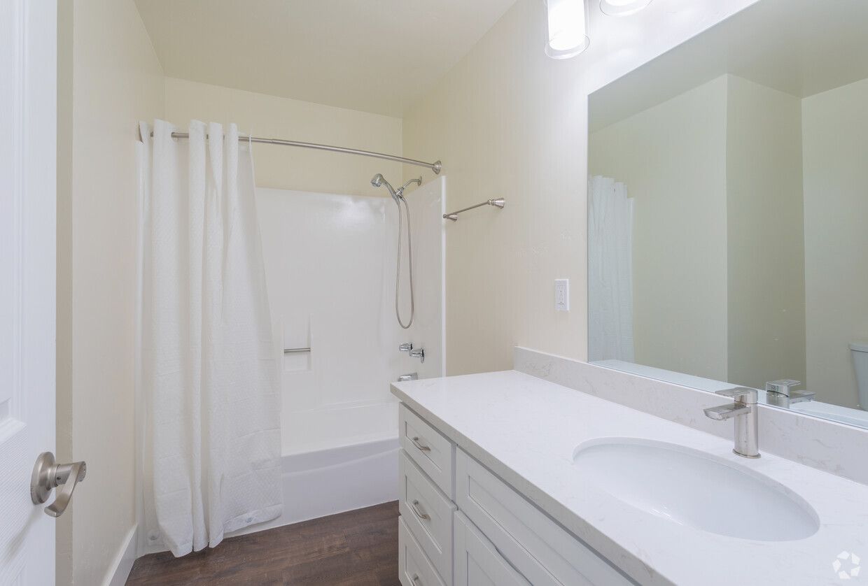 A bathroom with a sink , tub , shower and mirror.