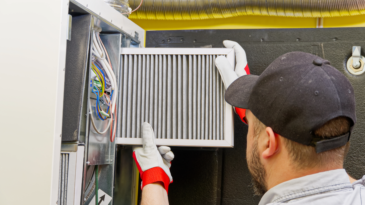 A man is holding a filter in his hands while working on an air conditioner.