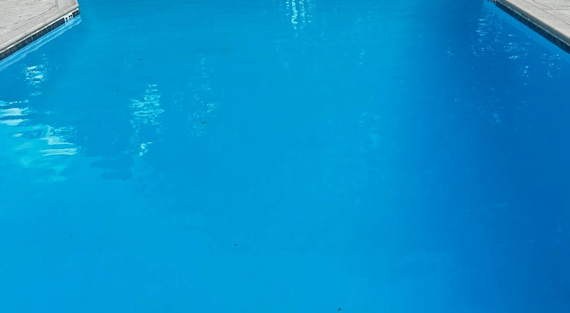 A close up of a blue swimming pool with a concrete border.