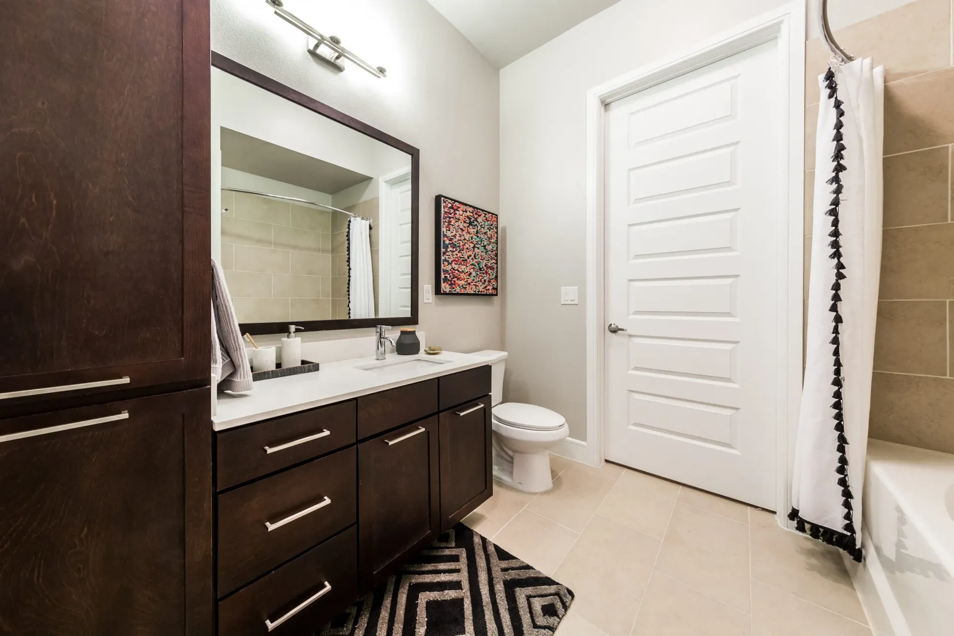 Modern bathroom with dark wood vanity, white countertop, and tiled shower.