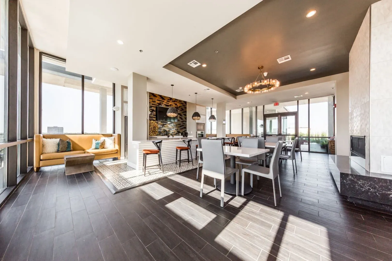 Comfortable seating area with a yellow sofa and coffee table, adjacent to a modern kitchen and dining area with bar stools and tables.