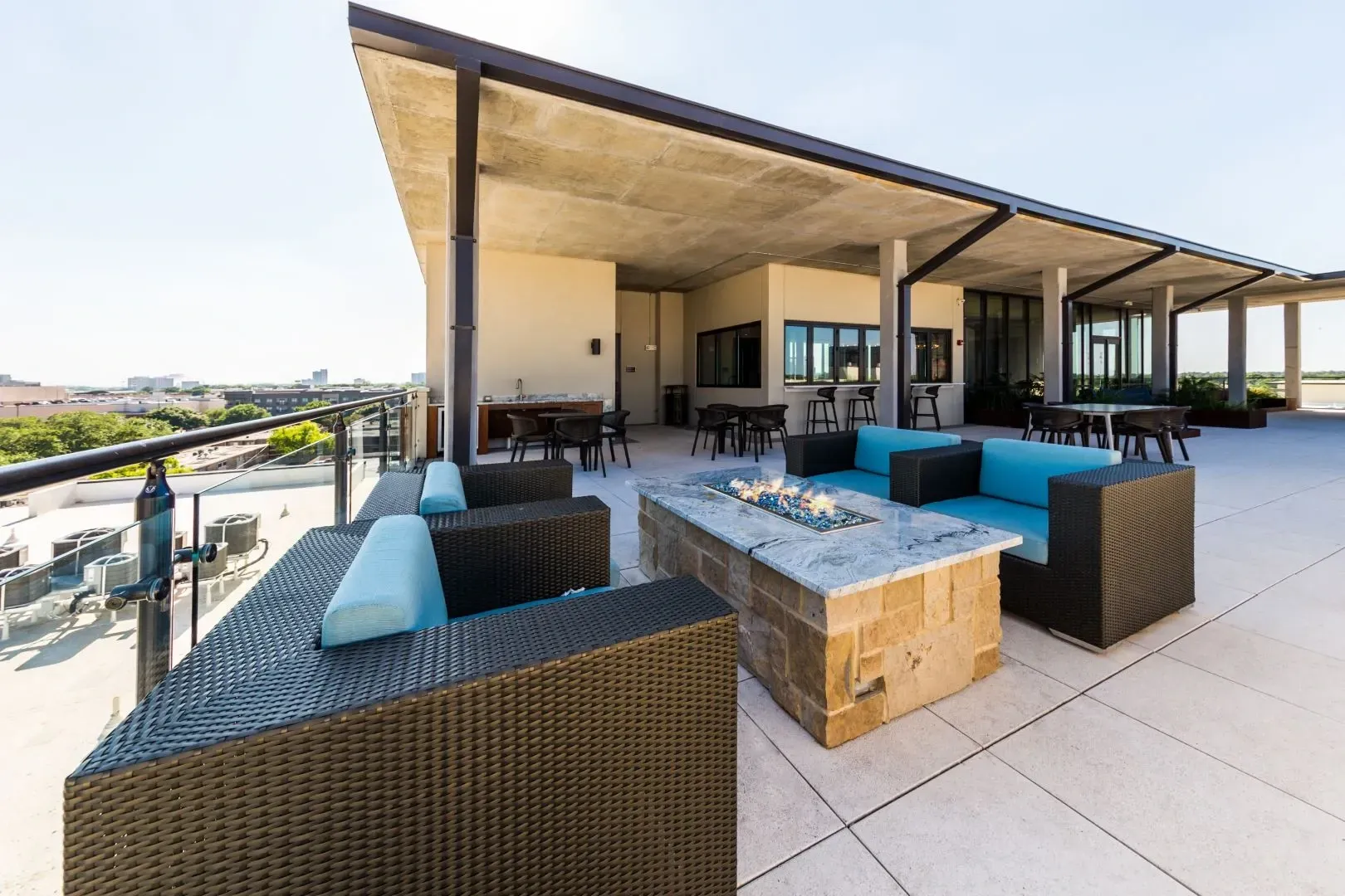 Modern rooftop lounge area with comfortable seating and a fire pit.
