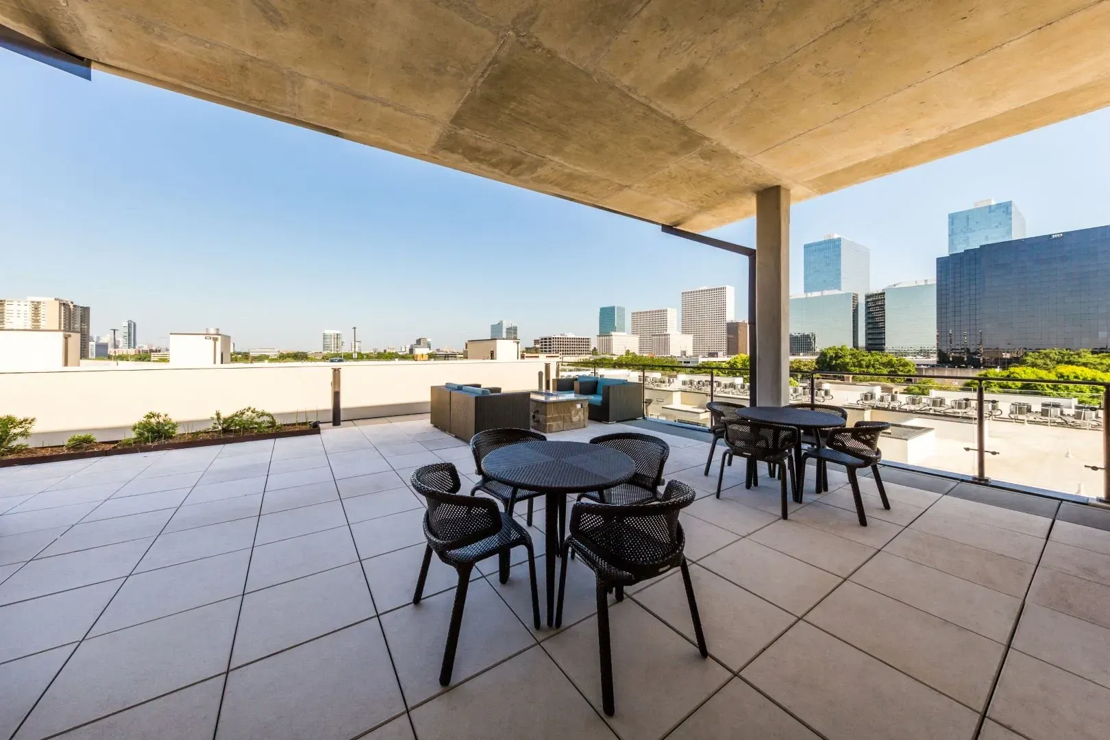 Rooftop patio with tables and chairs overlooking a city skyline.