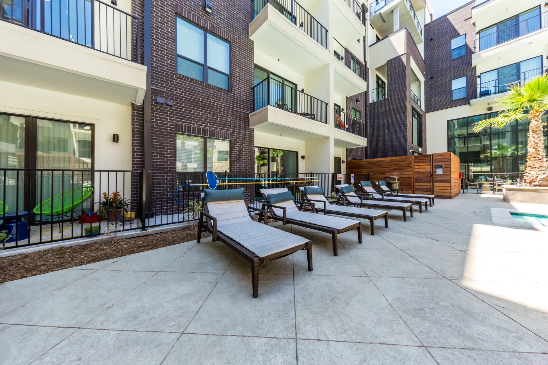 Chairs and lounge chairs next to a pool at an apartment complex.
