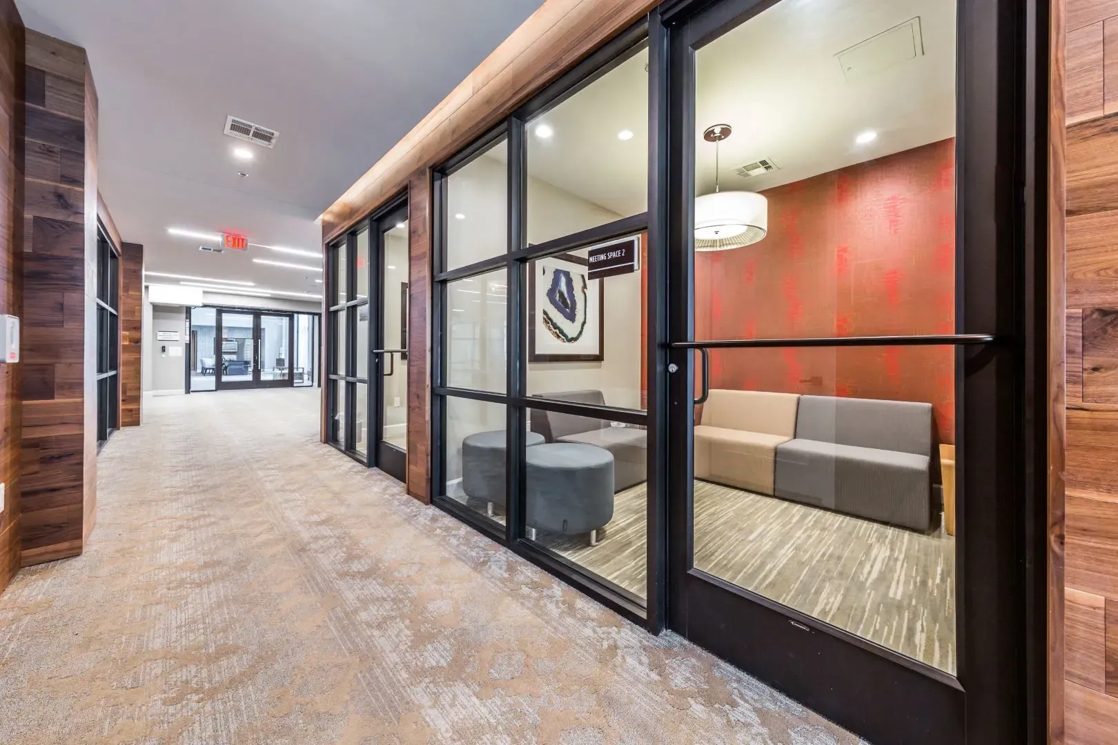 Hallway with wood paneling and glass doors leading to meeting spaces.