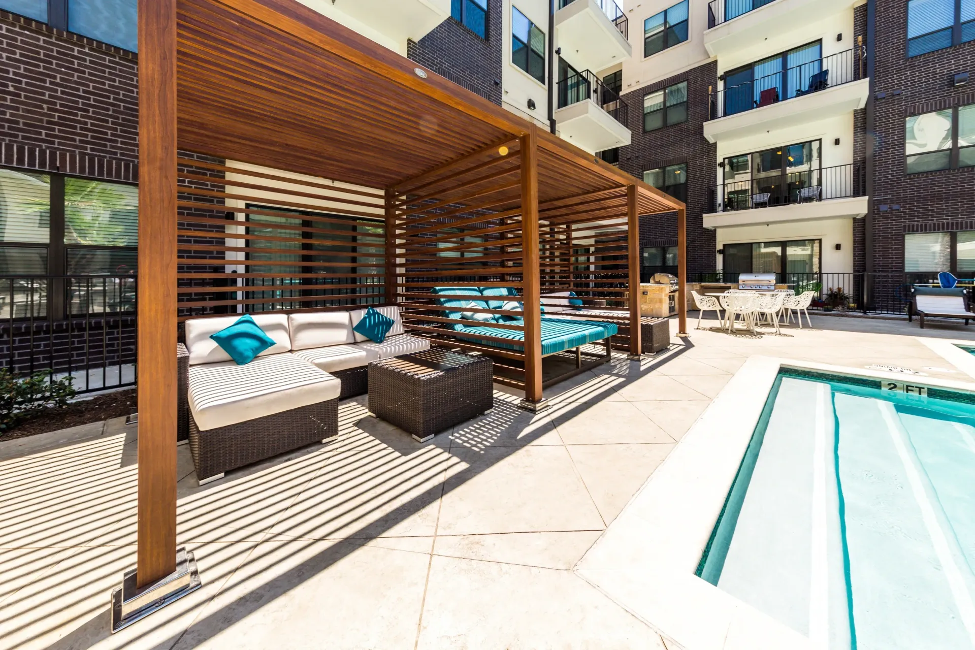 Outdoor lounge area with seating and a pool.