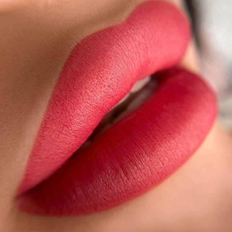 Close-up of red lipstick applied to a woman's lips, with a blurred background.