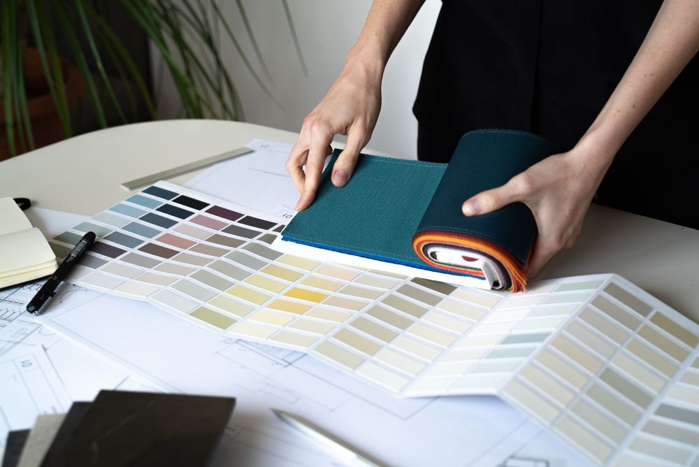 Person Selecting Teal Fabric From Color Swatches on a Table — Jamie Frankham Painting in Goonellabah, NSW