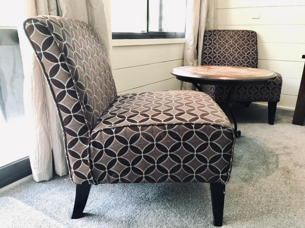 A chair with a pattern on it is sitting next to a table in a room.