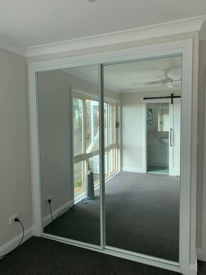 A bedroom with sliding glass doors and a mirrored wall.