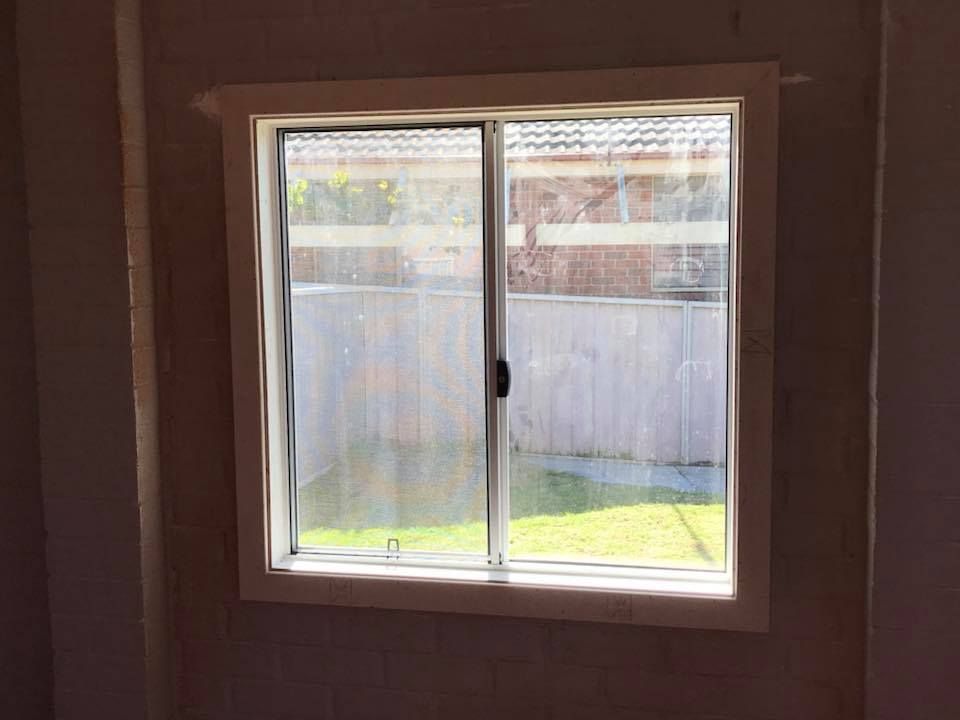 A window with a sliding glass door in a room with a fence in the background.