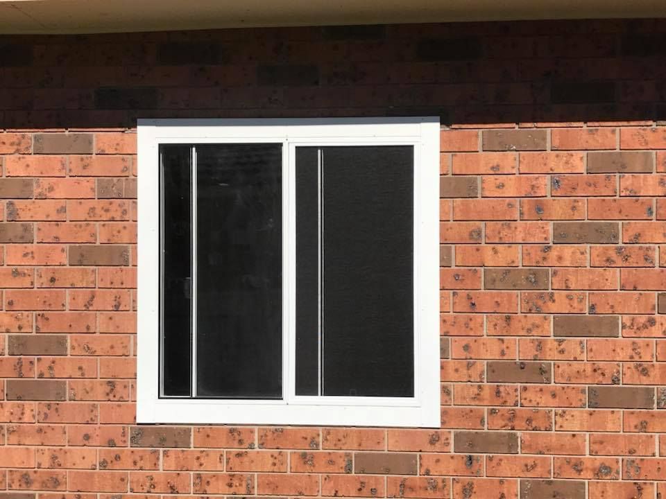 A white window is on a red brick wall.