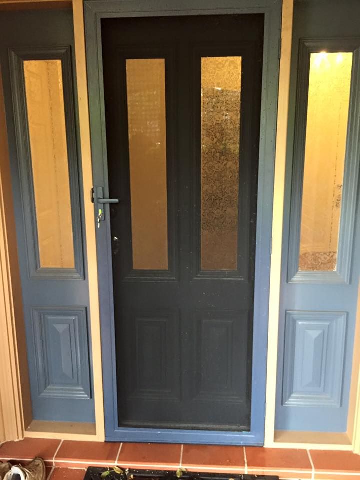 A blue door with a screen on it is sitting on a tiled floor.