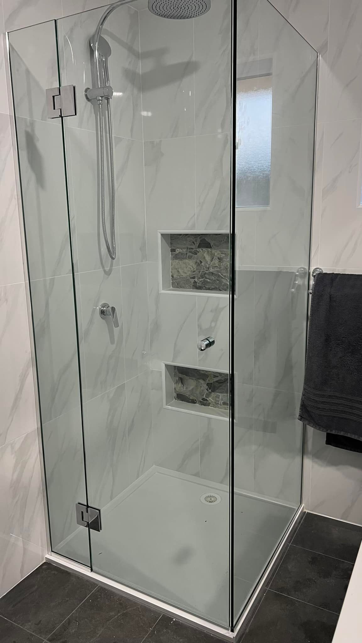 A bathroom with a walk in shower with a glass door.