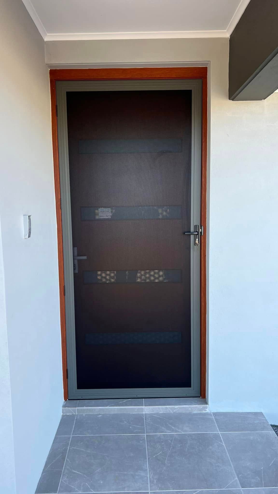 A door with a screen on it is on a white wall.